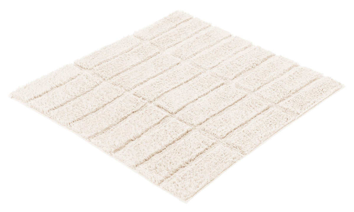 Quadratische, cremefarbene Badematte mit flauschigen Streifenstruktur