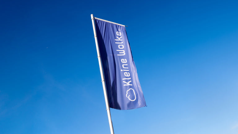 Blaue Fahne mit Aufdruck „Kleine Wolke“ und Wolkensymbol im Himmel
