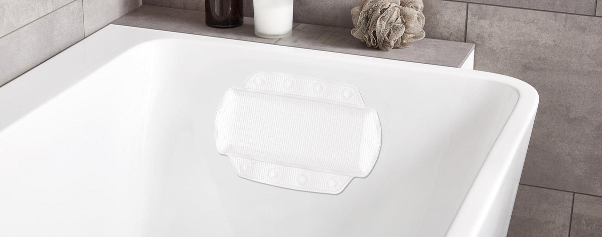 Weiße Badewanne mit rutschfestem Wannenkissen und Badaccessoires