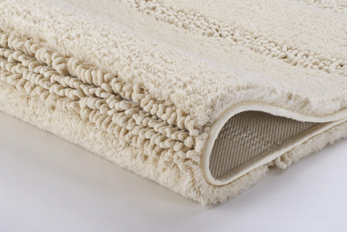 Gefaltete beige Badematte mit weicher, strukturierter Oberfläche aus Stoff
