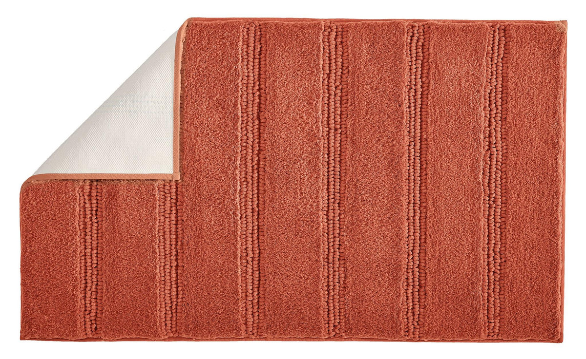 Rostrote Badematte mit Streifenstruktur und umgeknickter Ecke oben