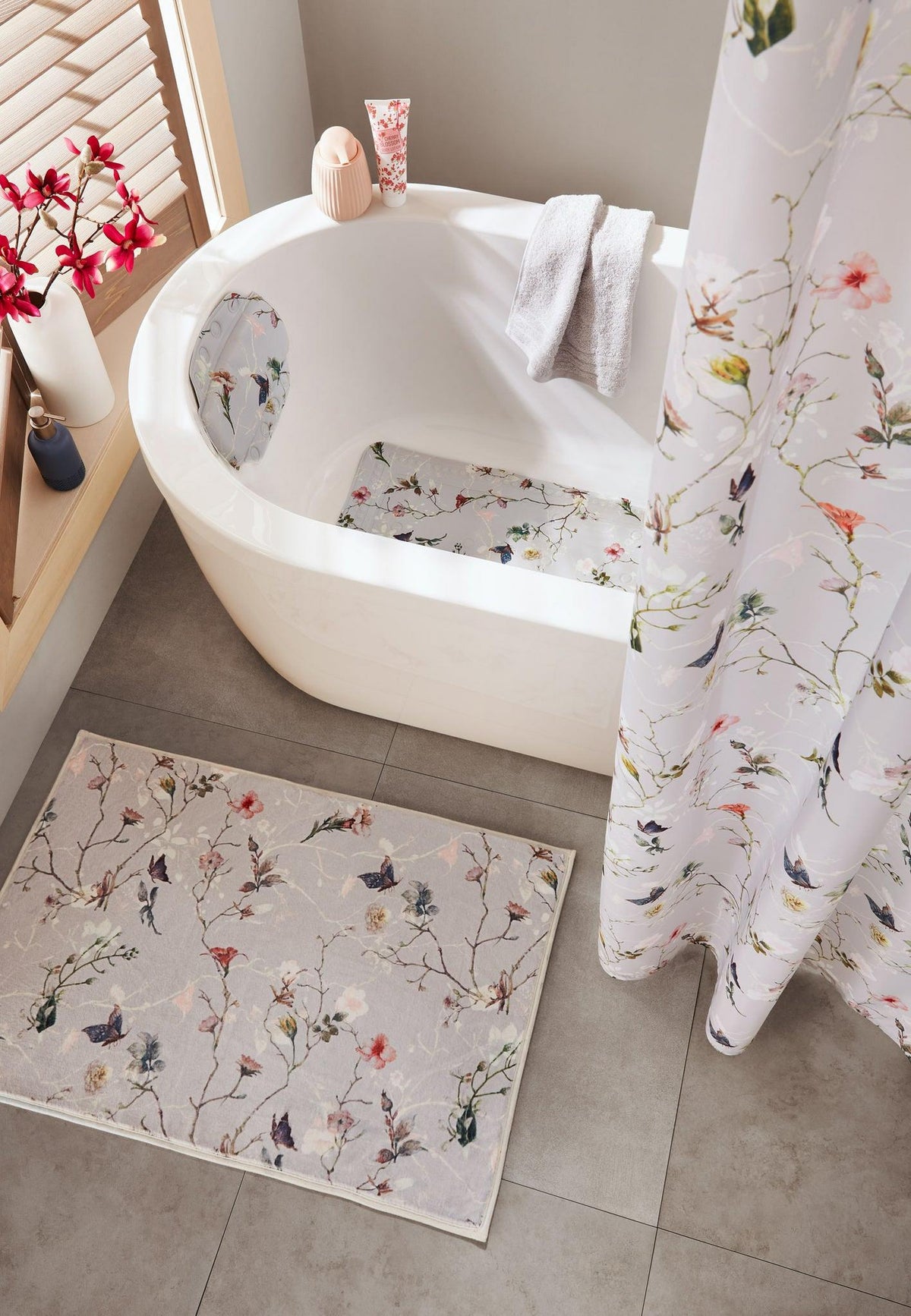 Helle Badewanne mit Blumenmuster-Duschvorhang und passender Badematte