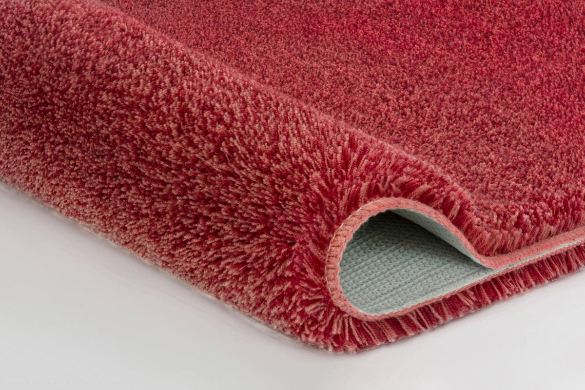 Nahaufnahme rosa Badteppich mit umgeschlagener Ecke und Rückseite