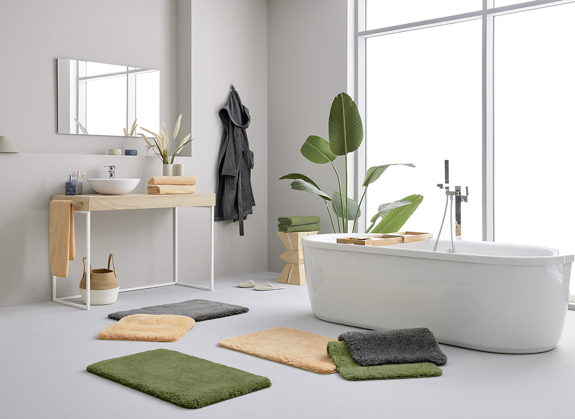Modernes Bad mit freistehender Wanne, Pflanzen und bunten Badematten