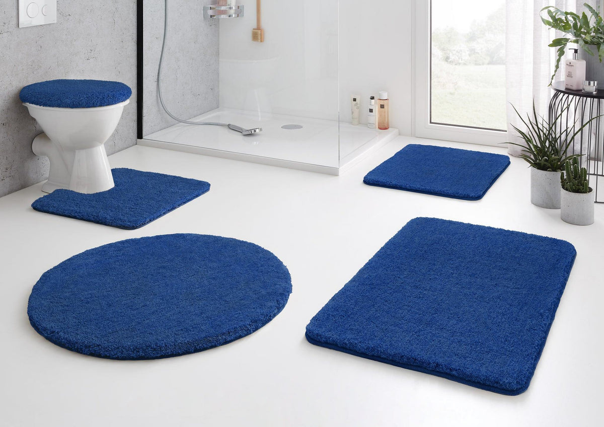 Badezimmer mit blauen Badematten-Sets vor Dusche und Toilette aus Stoff