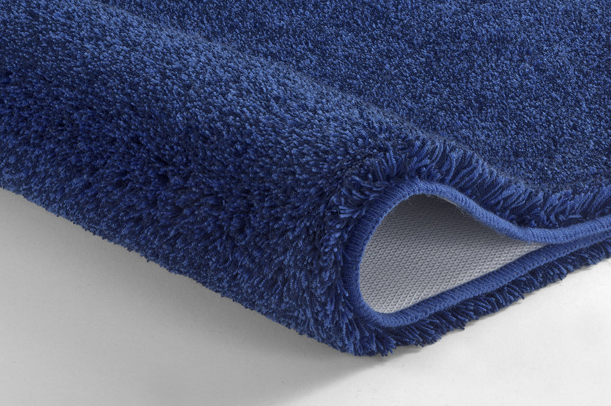 Nahaufnahme einer blauen Badematte mit umgeschlagener Ecke und Rückseite