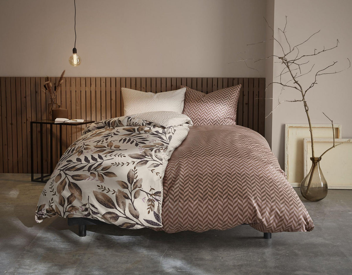Gemütliches Bett mit gemusterter Bettwäsche in Braun- und Cremetönen
