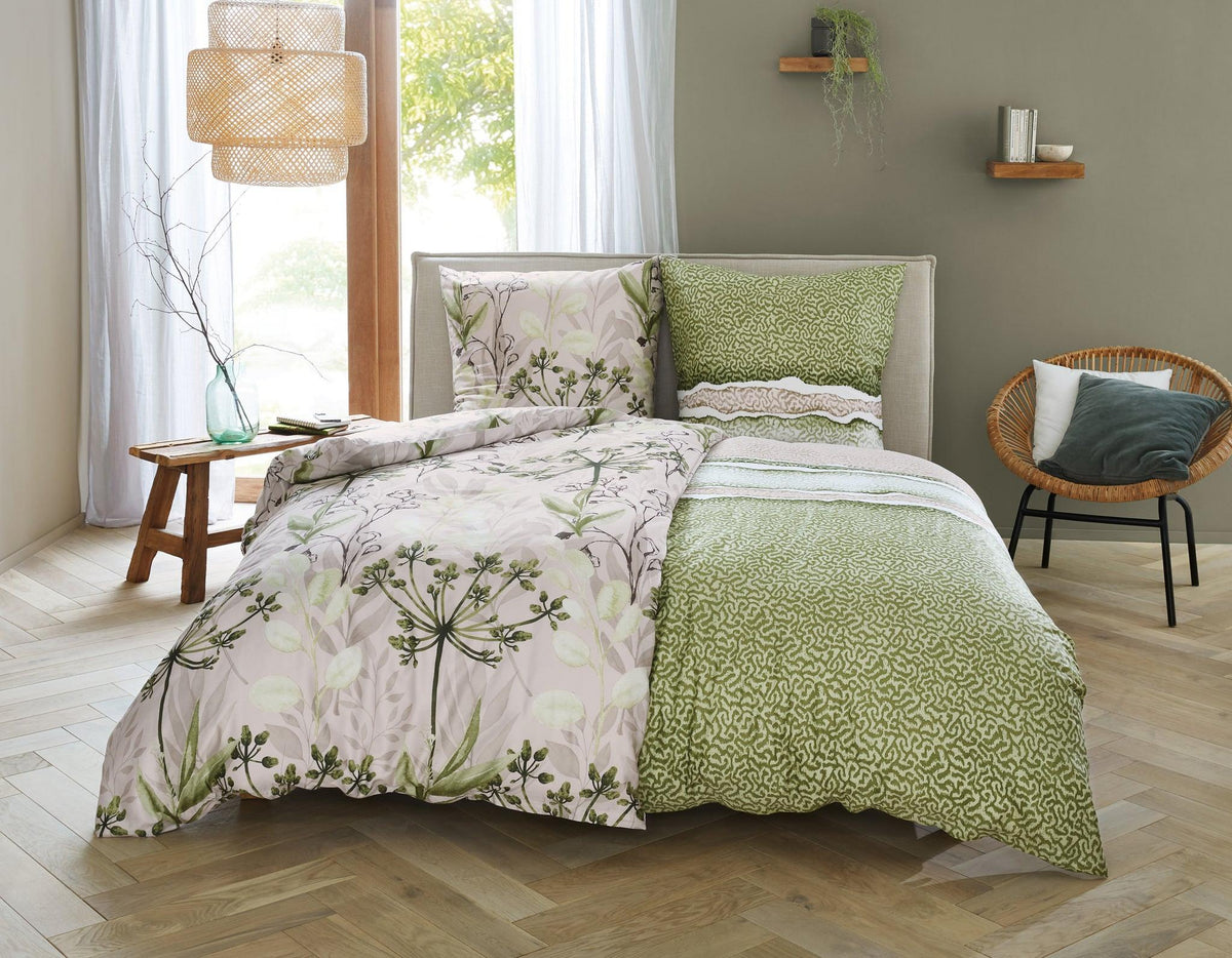 Doppelbett mit grün gemusterter Bettwäsche und floralem Deckenbezug