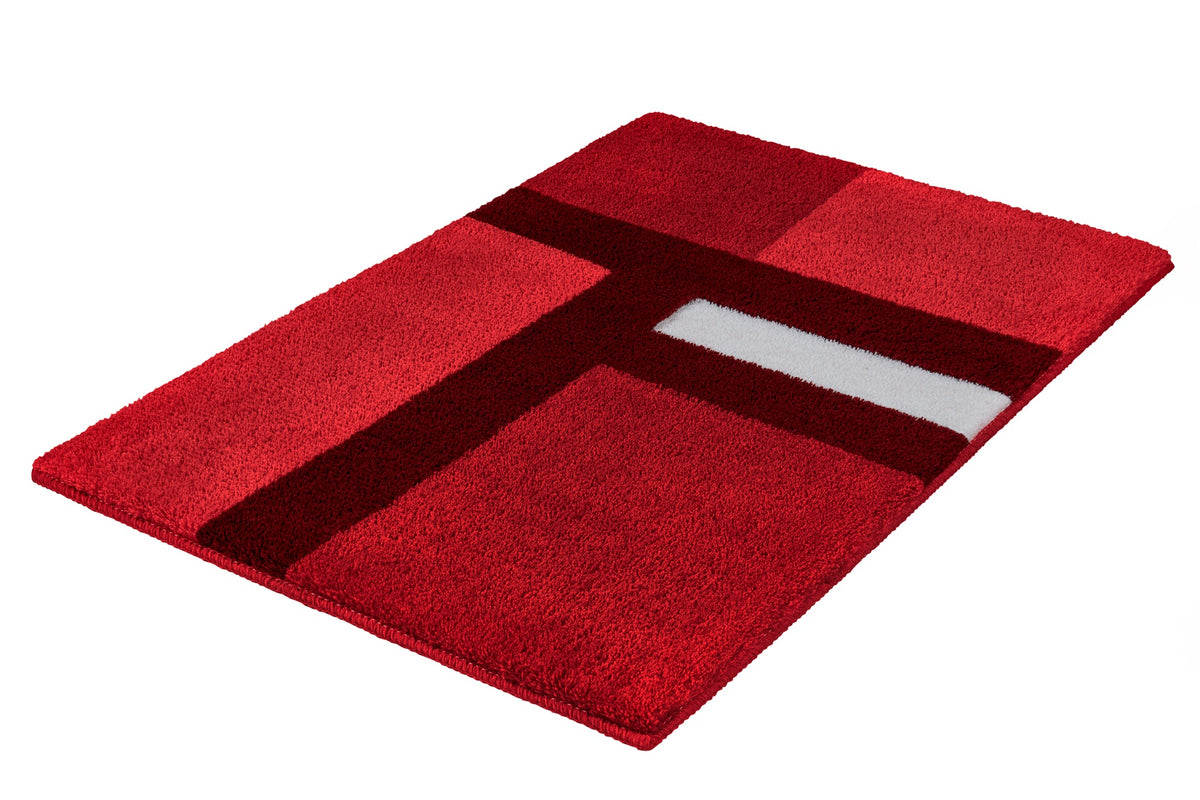 Ein roter Badteppich zeigt ein dunkelrotes Muster und einen weißen Streifen.