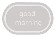 Ovaler hellgrauer Badteppich mit weißem Schriftzug good morning