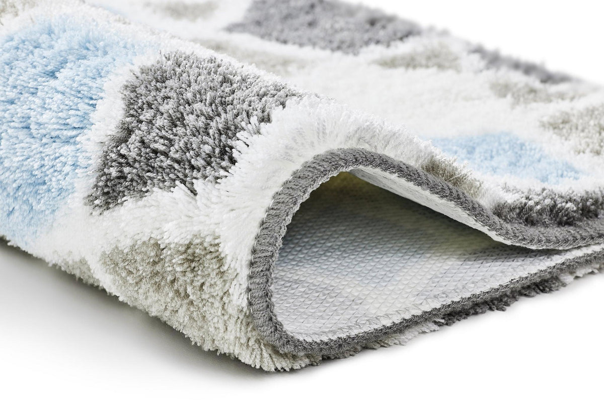 Nahaufnahme einer flauschigen Badematte mit blau-grau-weißem Muster
