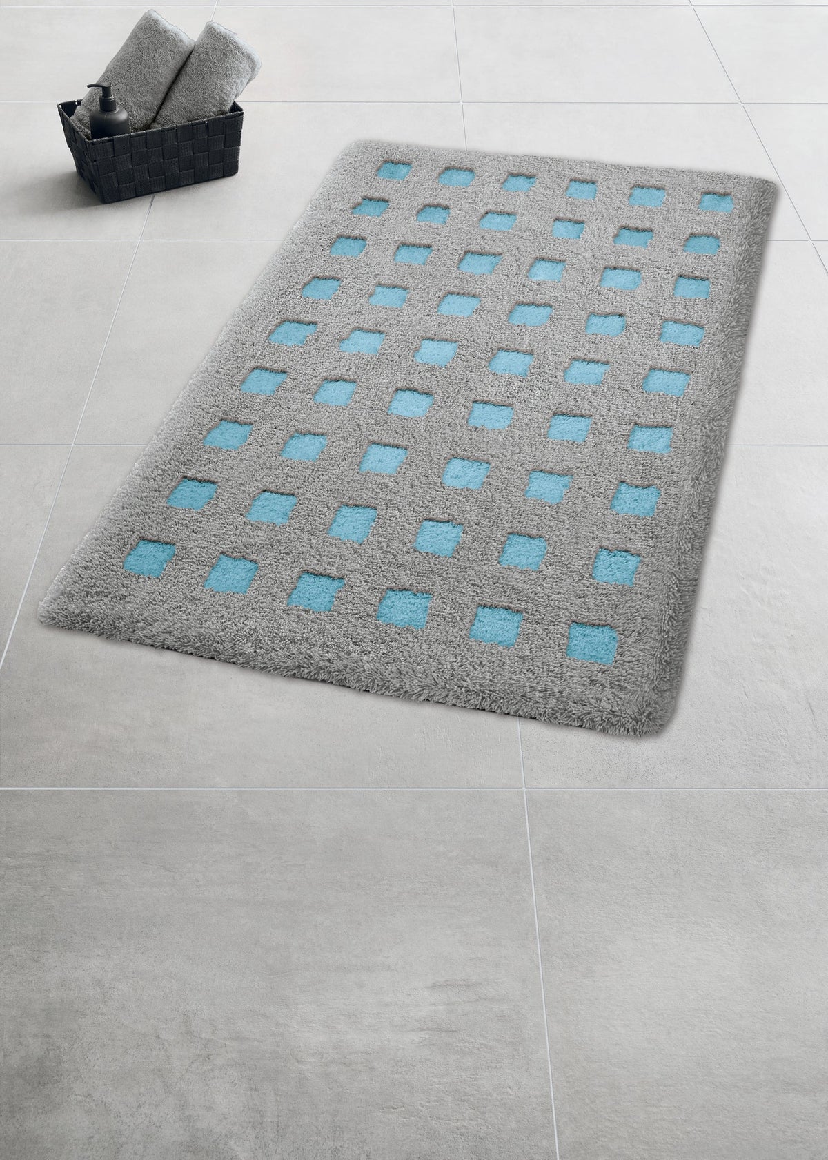 Graue Badematte mit blauen Quadraten auf hellgrauem Fliesenboden