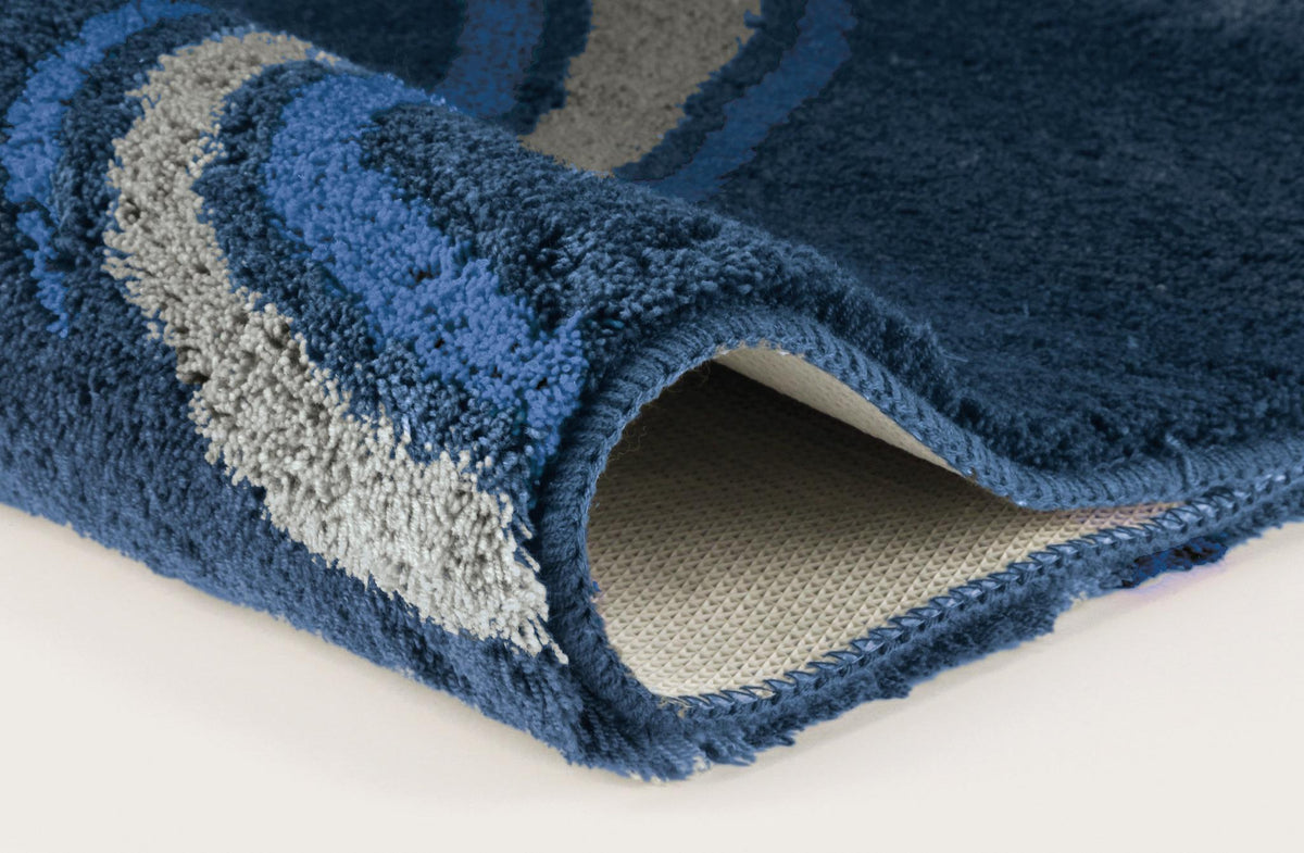 Nahaufnahme einer blauen Badematte mit grauen und hellblauen Wellen