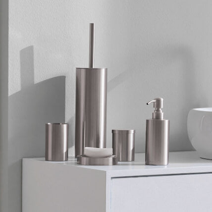 Silberfarbige Badaccessoires auf weißem Schrank neben Waschbecken.
