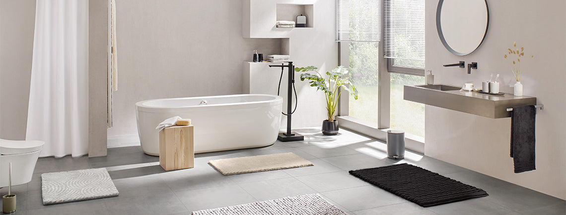 Helles Bad mit freistehender Wanne, Waschbecken und Badteppichen aus Stoff