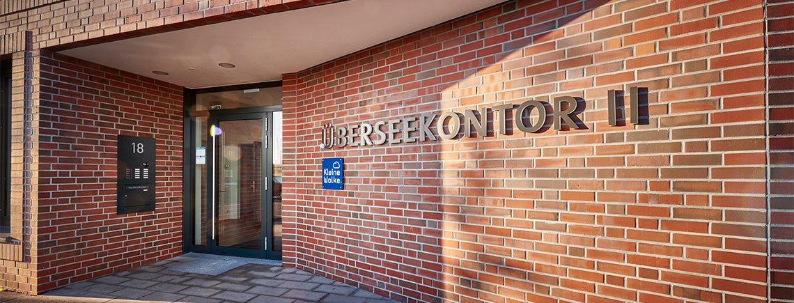 Backsteingebäude mit verglastem Eingang und Schriftzug ÜBERSEEKONTOR II