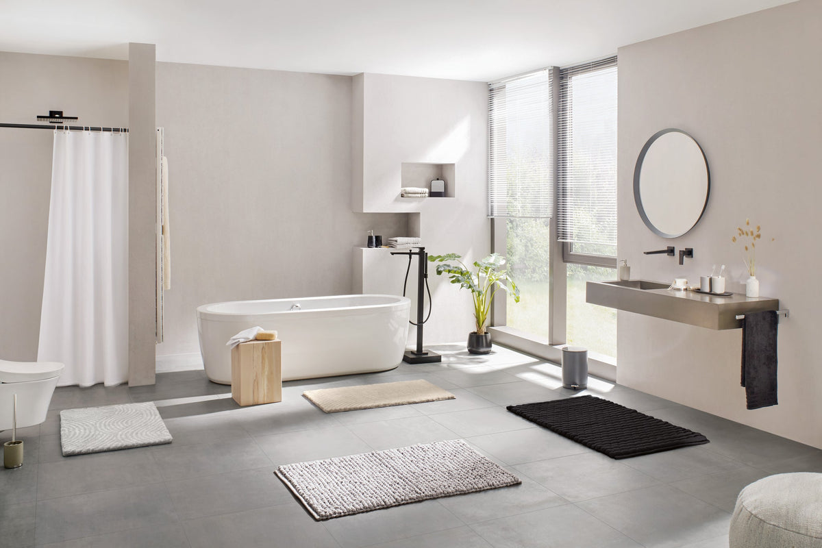 Modernes helles Bad mit freistehender Wanne und Badteppichen auf Boden
