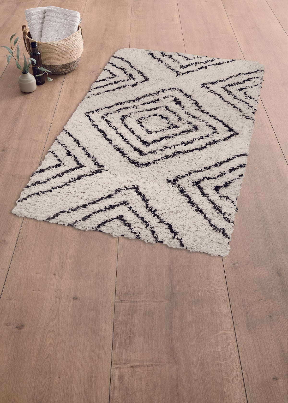 Weißer Badteppich mit schwarzem Muster auf Holzfußboden im Boho-Stil