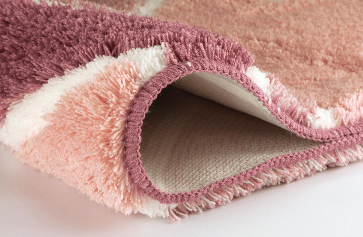 Nahaufnahme eines rosa-cremefarbenen Badteppichs mit sichtbarer Unterseite.