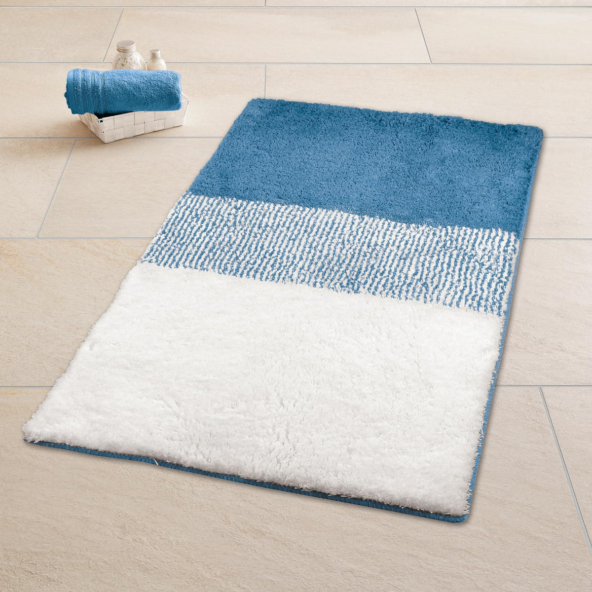 Blau-weißer Badteppich auf hellem Fliesenboden neben Korb mit Handtuch.