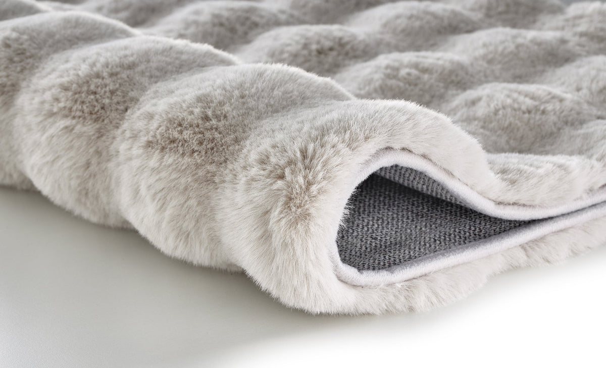 Nahaufnahme einer beigen, flauschigen Badematte mit Strukturoberfläche