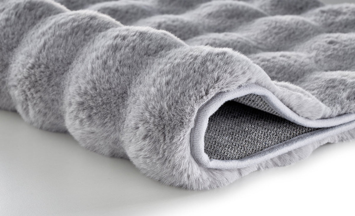 Detailansicht einer grauen, flauschigen Badematte mit weicher Oberfläche
