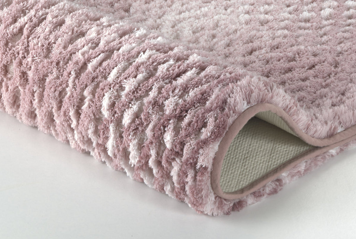 Nahaufnahme einer rosa, flauschigen Badematte auf weißem Hintergrund