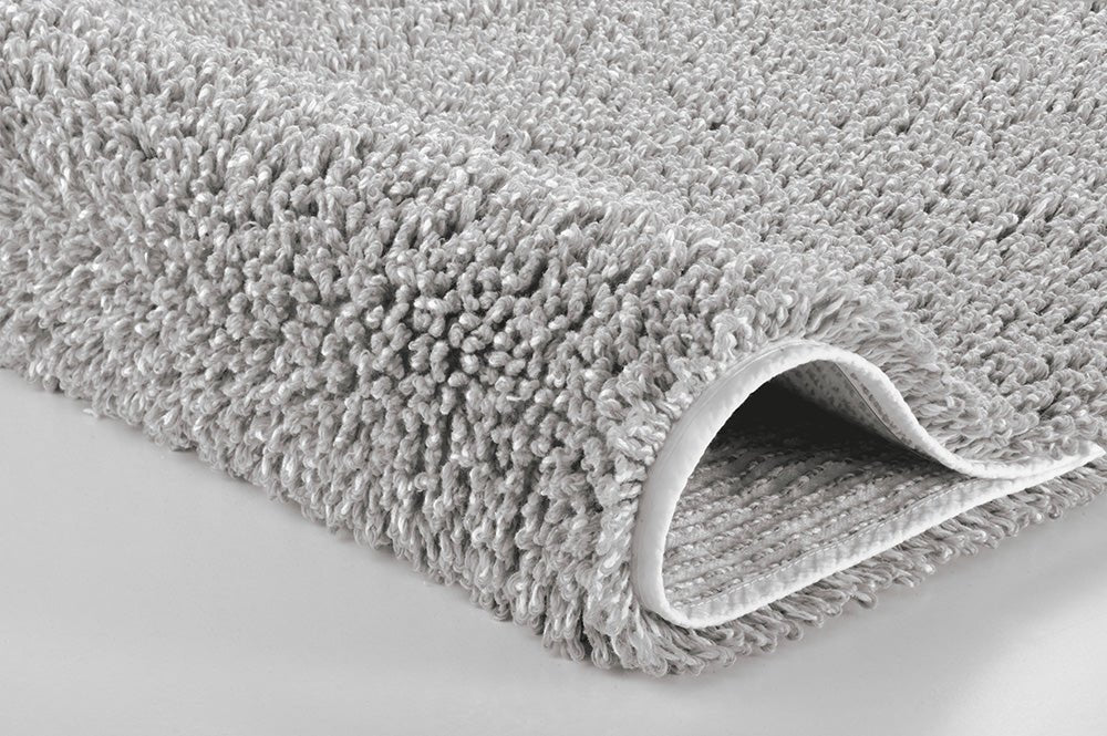 Nahaufnahme einer grauen Badteppich-Ecke mit dichtem Flor und Randdetail