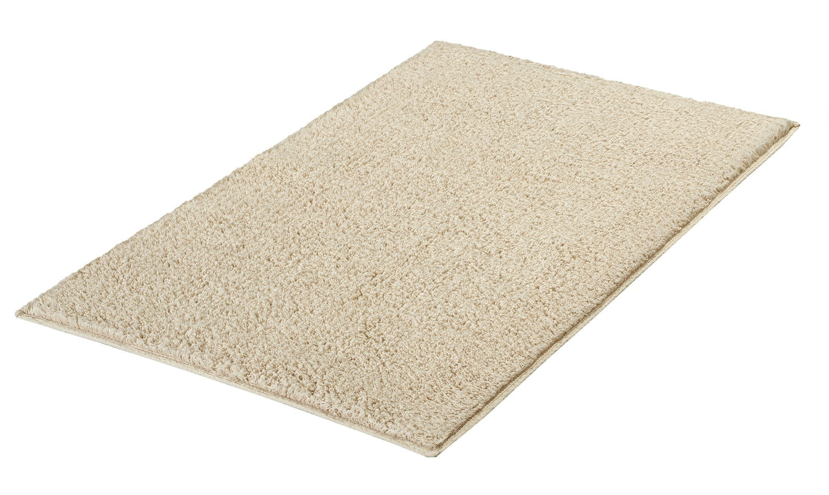 Rechteckige beige Badematte aus Hochflor auf Untergrund freigestellt