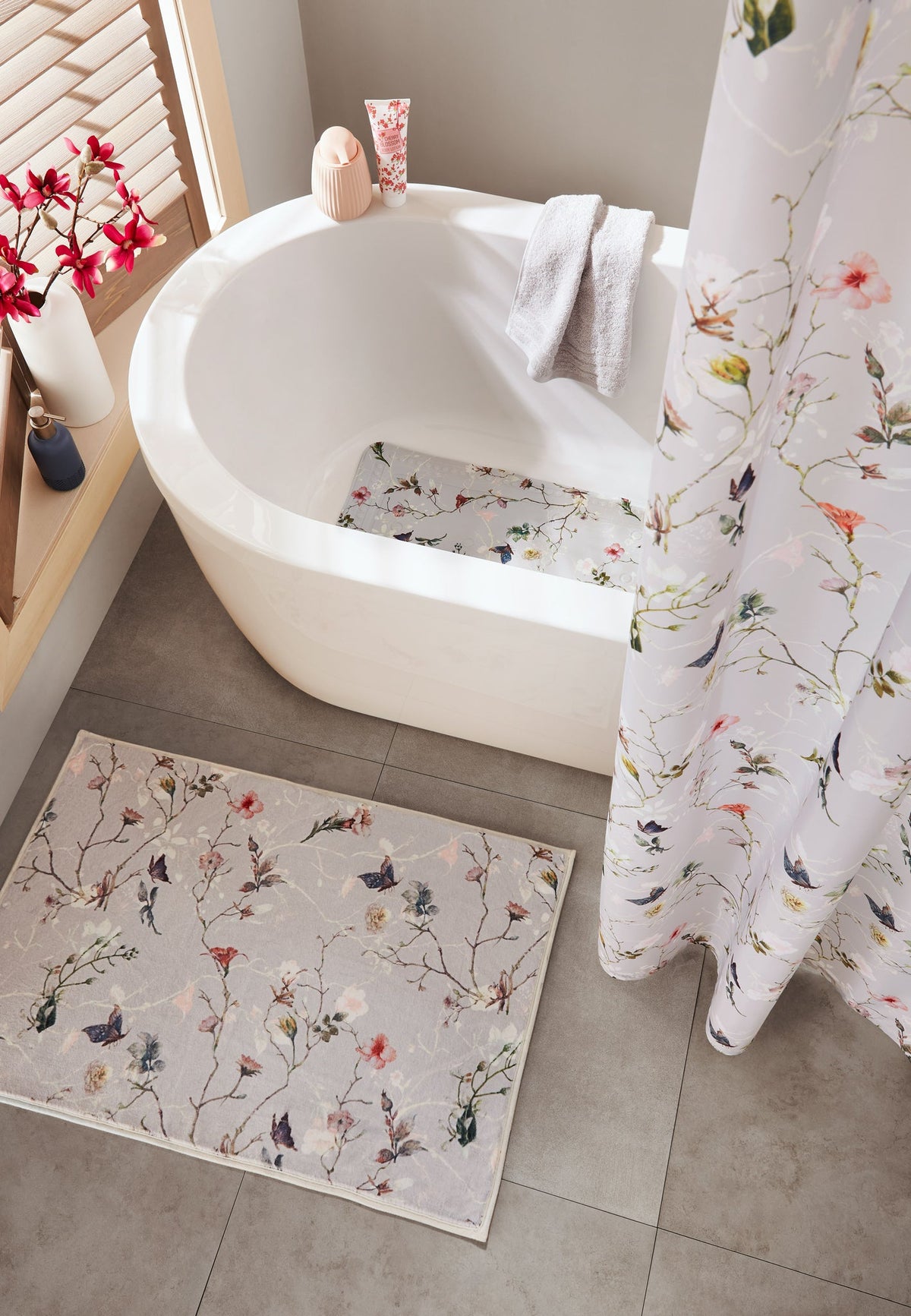 Badewanne mit floraler Badematte und passendem Duschvorhang in hellem Bad