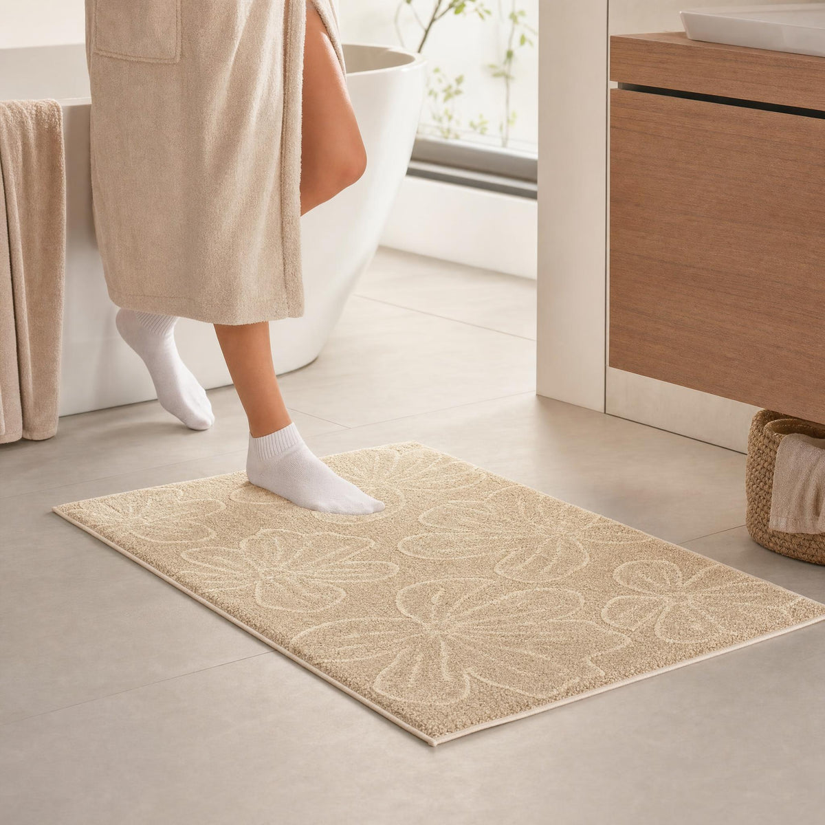 Beiger Badteppich mit Blumenmuster vor Badewanne in hellem Badezimmer.