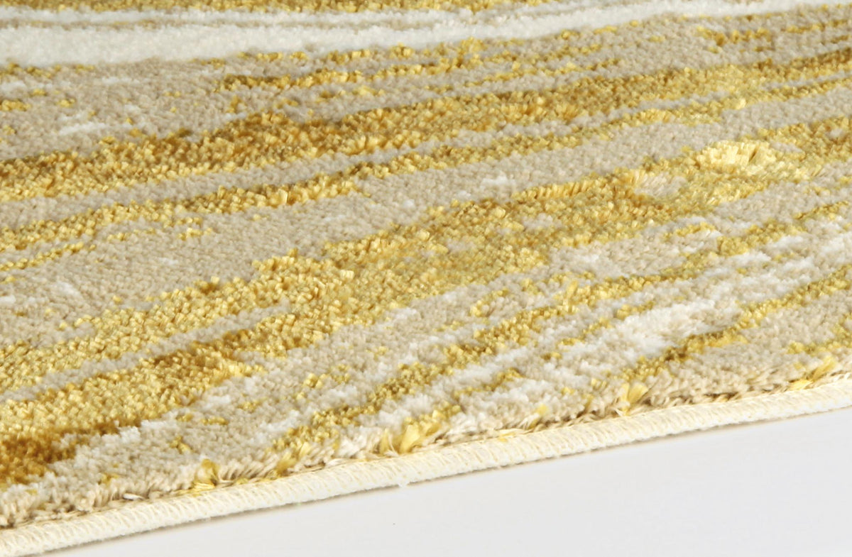 Nahaufnahme eines cremefarbenen Teppichs mit goldfarbigem Muster.