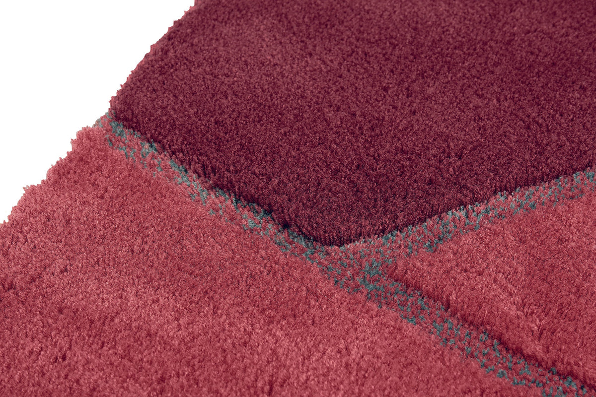 Nahaufnahme einer flauschigen Badematte in Rosa- und Bordeauxtönen