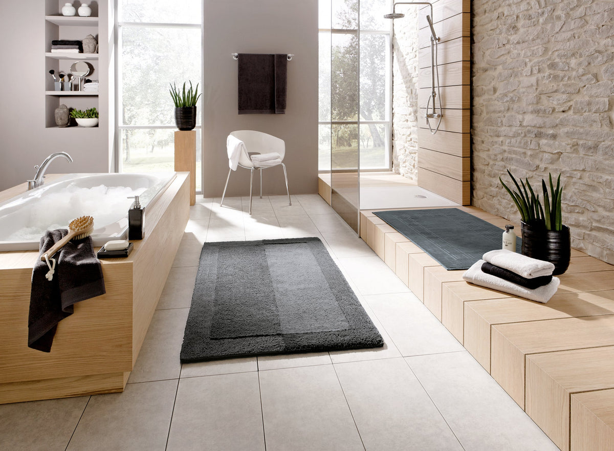 Modernes Badezimmer mit Wanne, offener Dusche und grauen Badteppichen