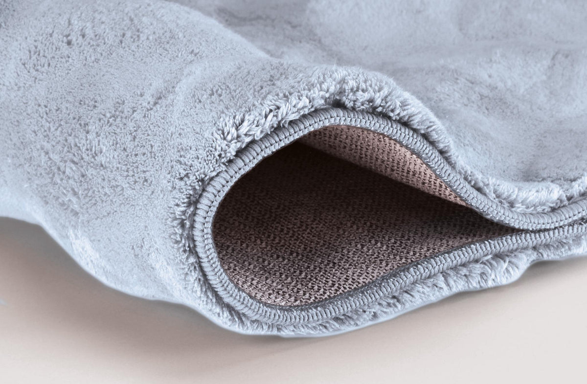 Hellblauer, flauschiger Badteppich mit umgeschlagener Ecke.