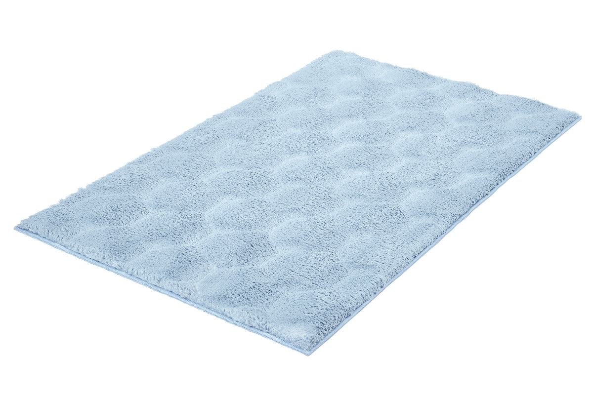 Hellblauer flauschiger Badteppich in rechteckiger Form auf weißem Grund.
