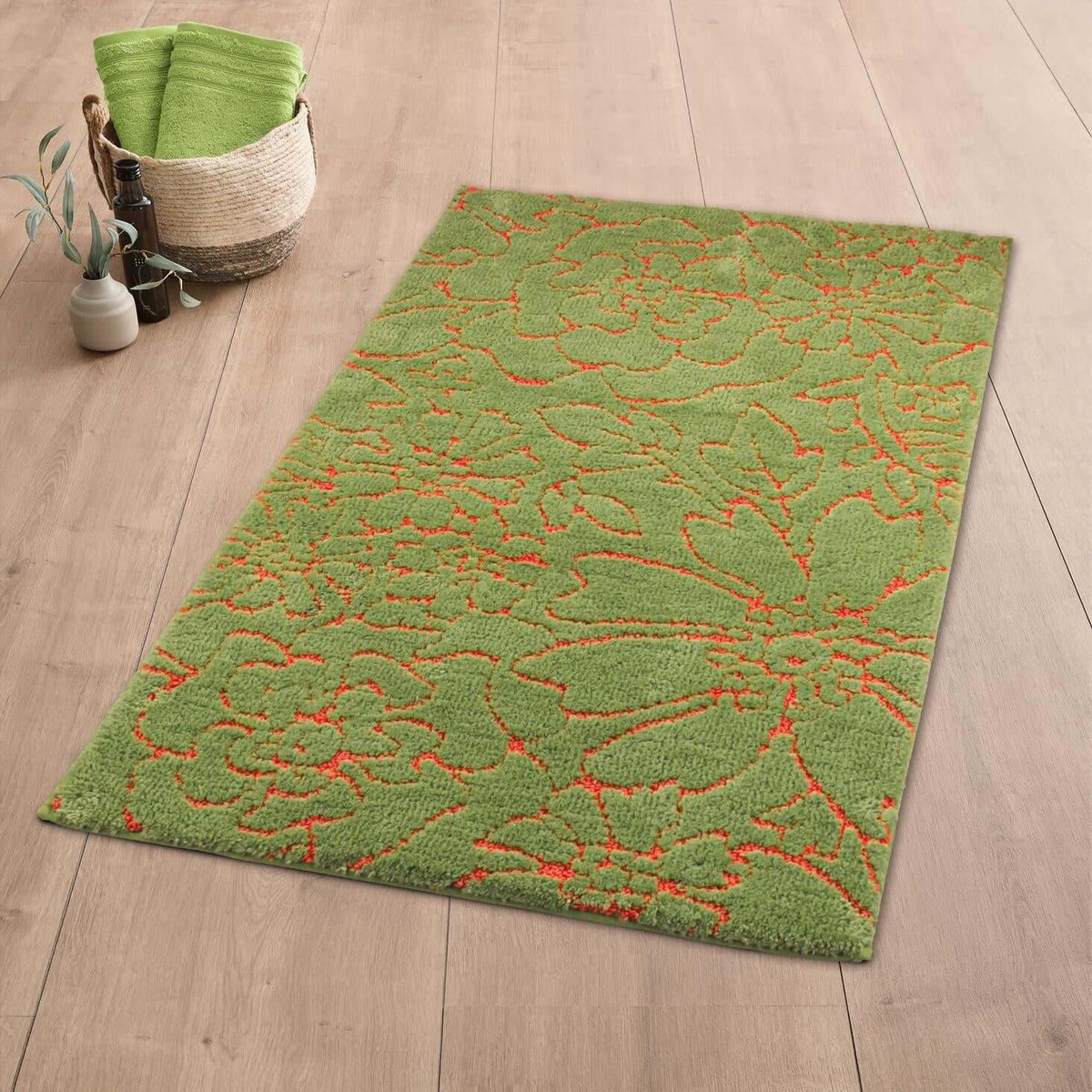 Grüner Badteppich mit orangefarbenem Blumenmuster auf hellem Holzboden.