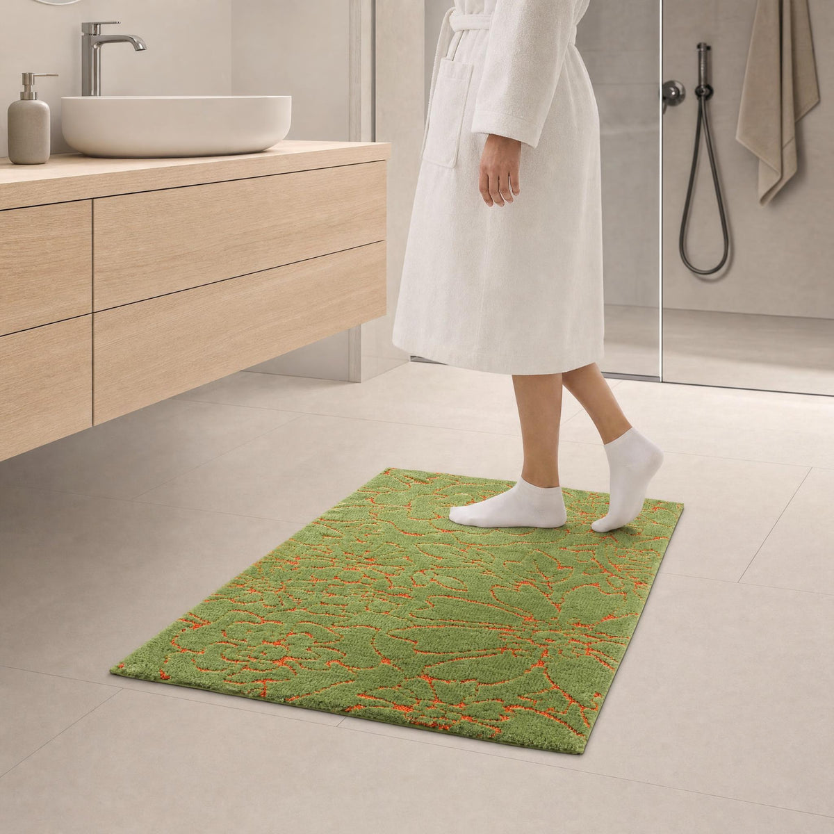 Person im Bademantel auf grünem Badteppich mit orangefarbenem Muster.