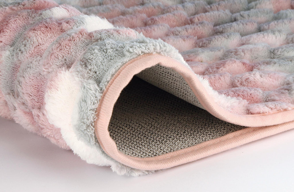 Gerollter flauschiger Teppich in Rosa, Weiß und Grau.