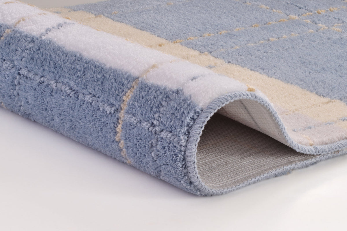 Gefaltete blau-beige Badematte mit Karomuster auf hellem Hintergrund