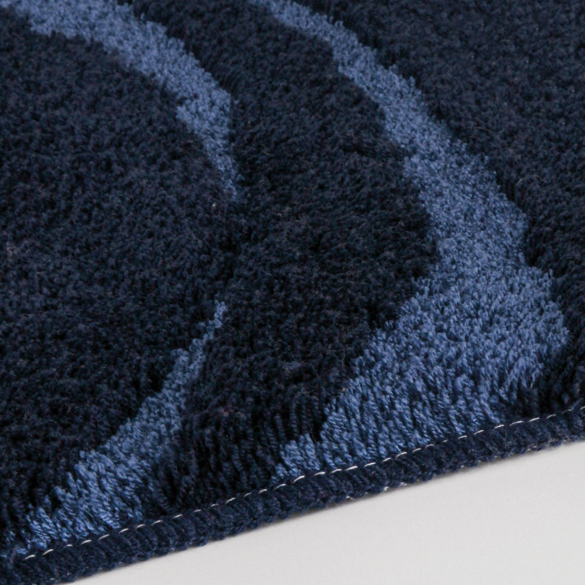 Dunkelblauer Badteppich mit hellblauen Wellenlinien in Nahaufnahme