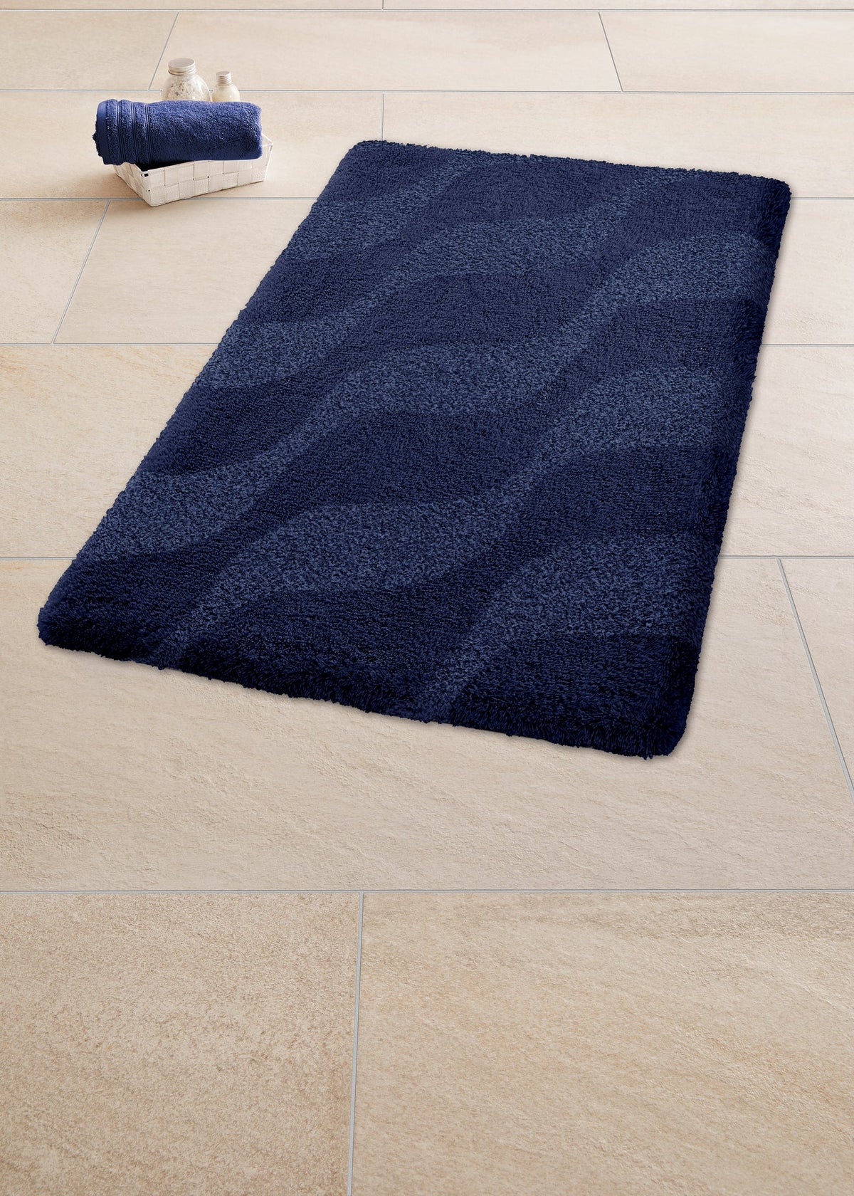 Dunkelblaue Badematte mit Wellenmuster auf hellen Fliesenboden aus Textil