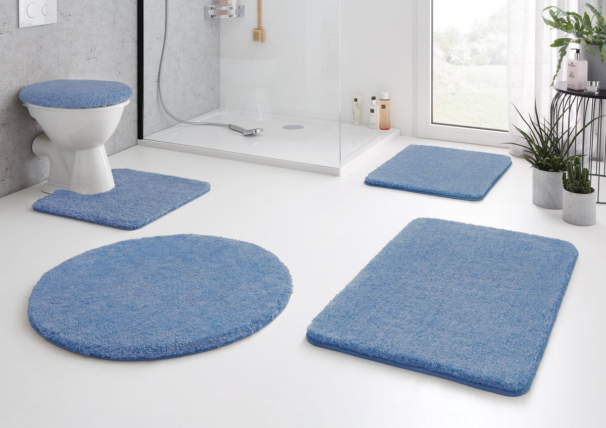 Modernes Bad mit blauen Badematten-Set und Duschvorlegern auf Boden