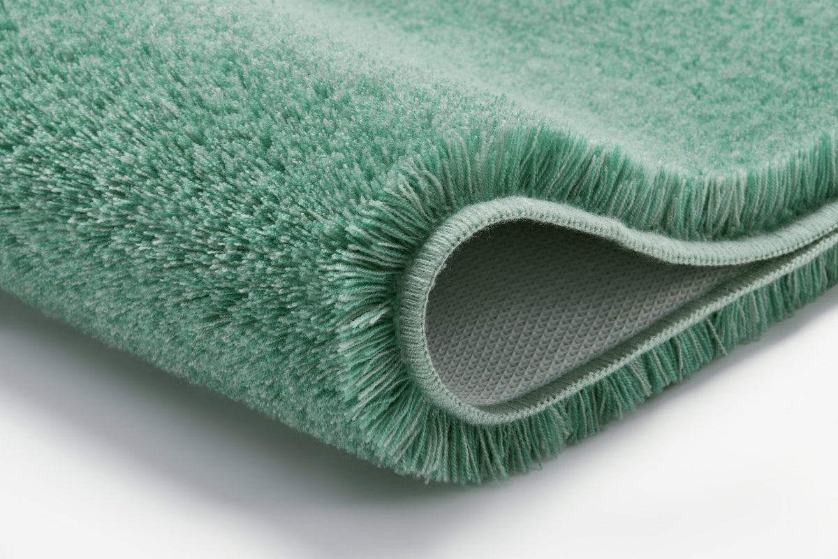 Nahaufnahme einer gefalteten, mintgrünen Badematte mit weichem Flor