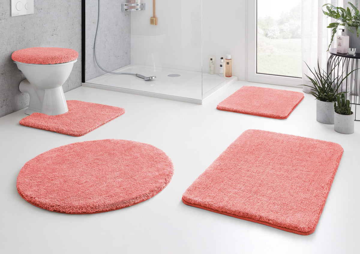 Korallfarbenes Badematten-Set im modernen Bad mit Dusche und WC