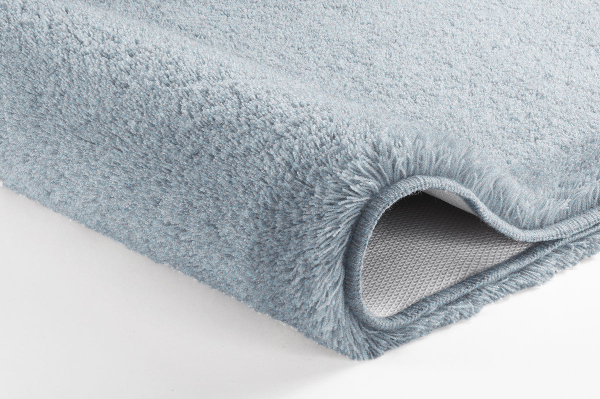 Hellblaue, flauschige Badematte im Detail mit rutschhemmender Unterseite