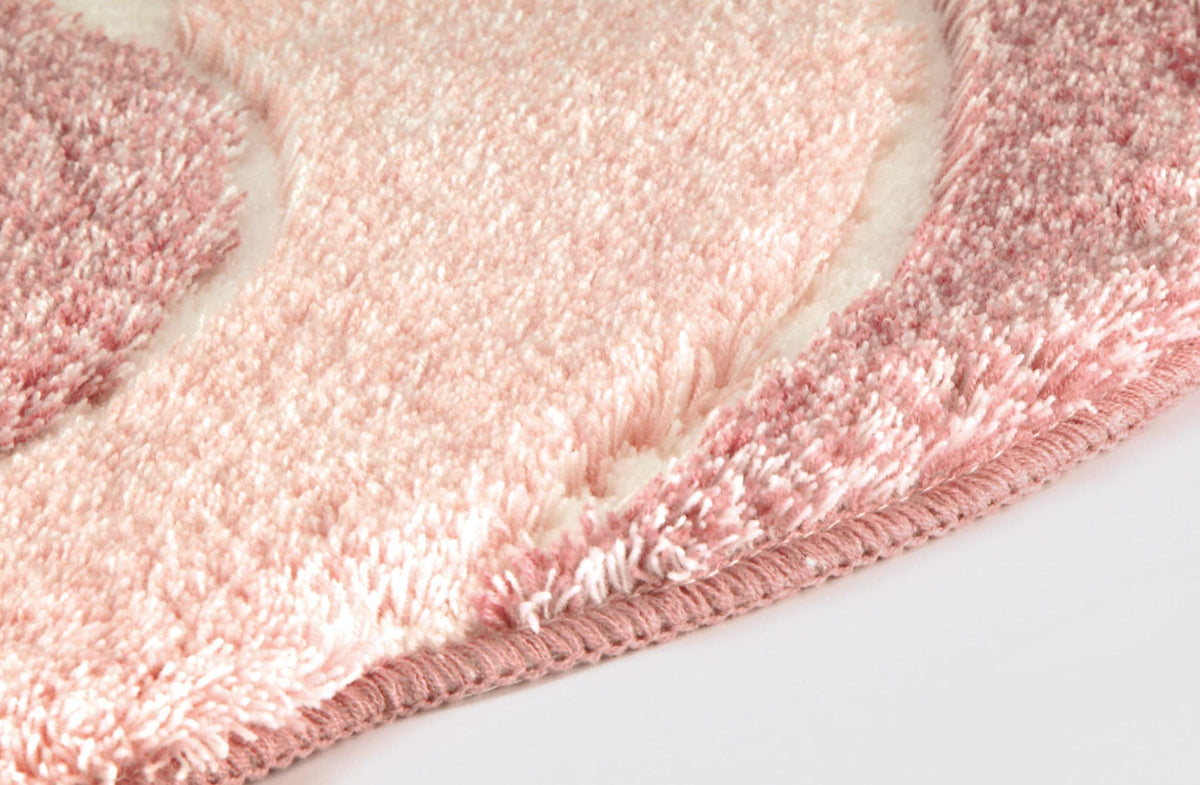 Detailansicht eines rosa Badteppichs mit weicher, flauschiger Struktur.
