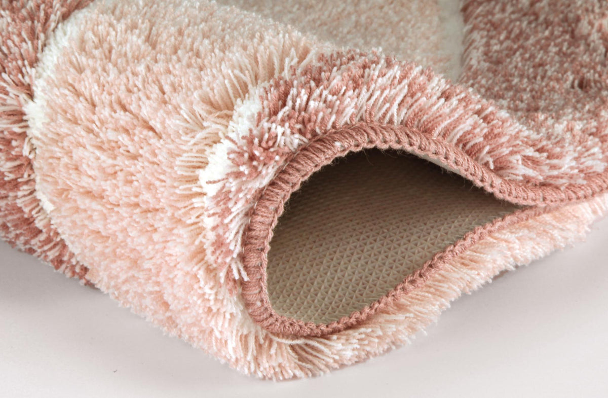 Rosafarbiger, flauschiger Badteppich mit rutschfester Unterseite.