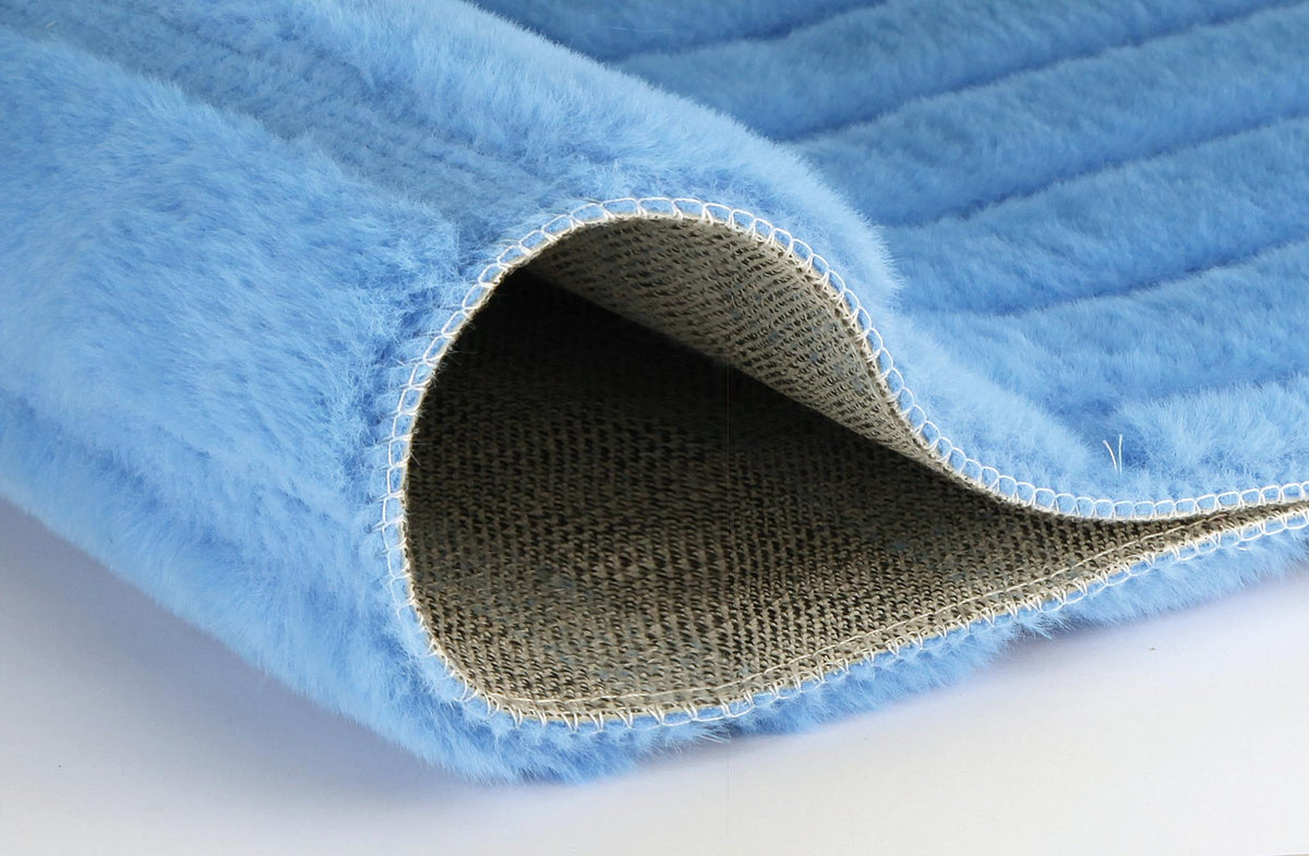 Hellblaue flauschige Matte mit umgeklappter Ecke und rutschfester Unterseite.