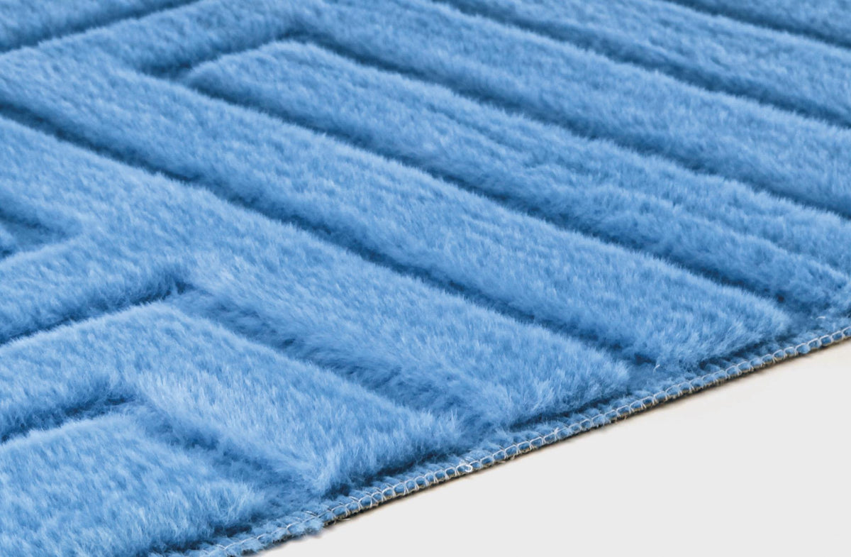 Nahaufnahme eines hellblauen, flauschigen Teppichs mit gerippter Struktur.